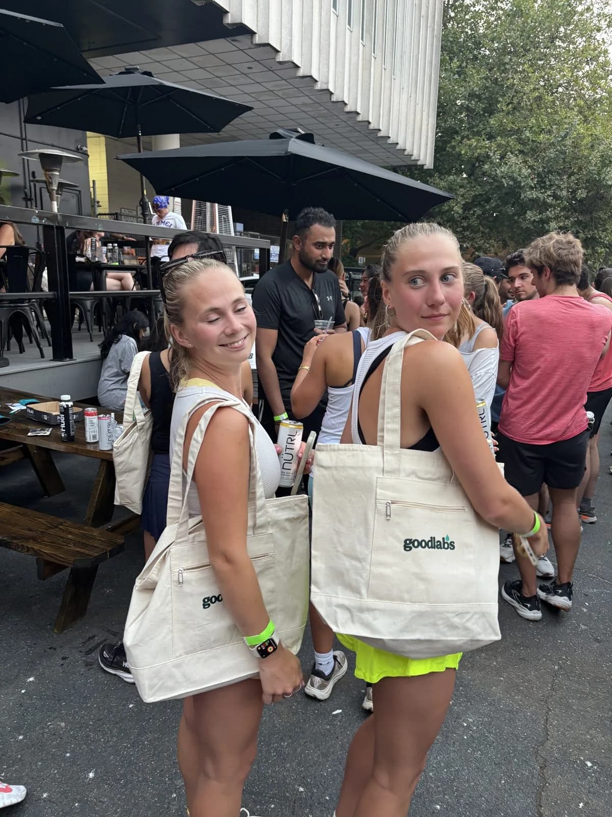 Two friends carrying Goodlabs tote bags at a run club hangout